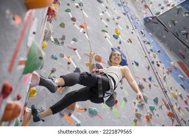 Smiling woman climbing indoor rock wall - Powered by Shutterstock