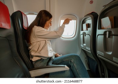 Smiling Woman Closing Window During Flight On Plane