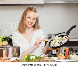 Smiling Woman Cooking Fish With Lemon In Frying Pan At  Kitchen 