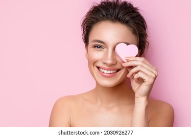 Smiling Woman With Cosmetic Sponge Covering One Eye. Photo Of Woman With Perfect Makeup On Pink Background. Beauty Concept