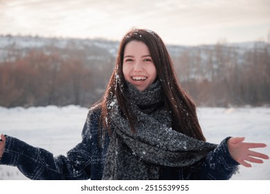 A smiling woman covered in snow standing in a winter field, enjoying the cold and fresh air of a snowy day. Joy and energy in a natural winter setting. - Powered by Shutterstock