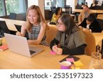 Smiling woman with coworker with Down Syndrome looking at laptop in modern office