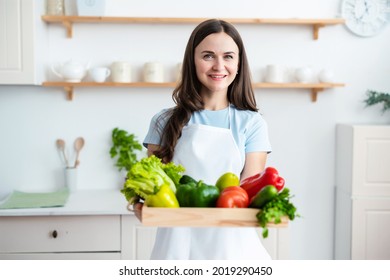 Smiling woman culinary chef wearing white apron is holding wooden tray with healthy fresh vegetables. Food, culinary bloggers concept. - Powered by Shutterstock