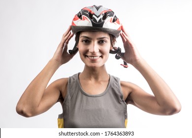 Smiling Woman Cyclist Fastens The Technical Helmet, Isolated On Light Background