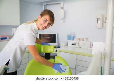 Smiling Woman Dentist Cleaning Up Dentist Chair After Procedures.