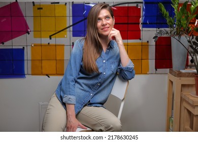 Smiling Woman Designer Student Or Teacher In Classroom With Color Palette Sitting On Chair And Looking Up