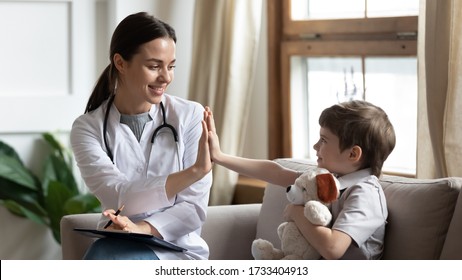 Smiling Woman Doctor Or Nurse Give High Five To Excited Little Boy Patient At Consultation In Clinic, Happy Small Child Have Fun Greet With Female Pediatrician In Hospital, Healthcare Concept
