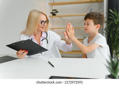 Smiling Woman Doctor Or Nurse Give High Five To Excited Little Boy Patient At Consultation In Clinic, Happy Small Child Have Fun Greet With Female Pediatrician In Hospital, Healthcare Concept.