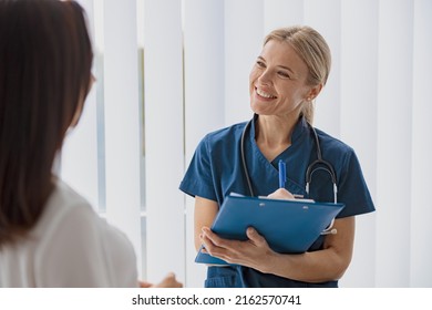 Smiling woman doctor taking notes on clipboard and looking on patient in medicine center - Powered by Shutterstock