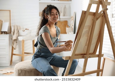 Smiling woman drawing picture on canvas in studio - Powered by Shutterstock