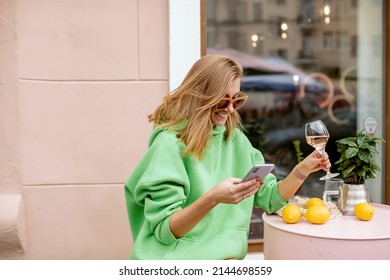 Smiling Woman Drinking Wine And Texting On Phone At Outdoor Cafe. Copy Space.