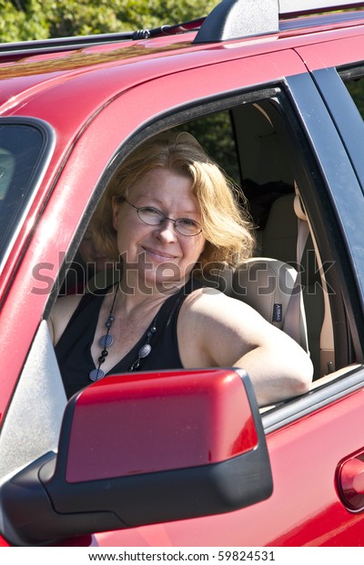 smiling woman drives a red\
car