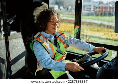Smiling woman driving a bus while working as professional driver.