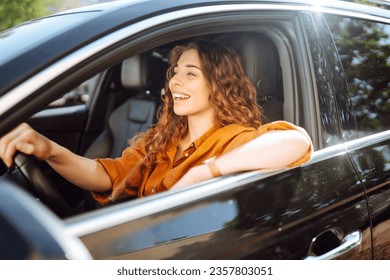 Smiling woman driving a car. Attractive woman sitting in the driver's seat of a car. Outdoor portrait. The concept of transport, lifestyle.