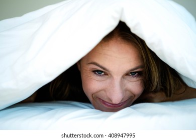 Smiling Woman With A Duvet Pulled Over Her Head