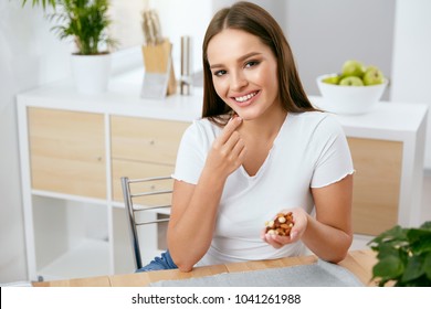 Smiling Woman Eating Nuts In Kitchen