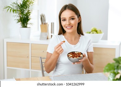 Smiling Woman Eating Nuts In Kitchen