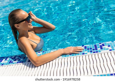 Smiling Woman At The Edge Of A Swimming Pool And Looking At Camera.