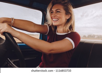 Smiling Woman Enjoying Driving A Car. Cheerful Female Going On A Road Trip By A Old Truck.