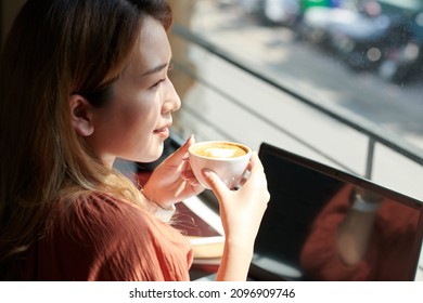 Smiling Woman Enjoying Morning Coffee In Coffeeshop And Looking On Through Big Window
