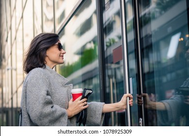 Smiling Woman Entering In Residential Building. Happy Businesswoman Coming To Work And Entering In Office Building.