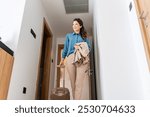 A smiling woman enters a hotel room, pulling her suitcase behind her and holding a jacket. She looks ready to settle in, with a modern, minimalist hotel setting in the background.