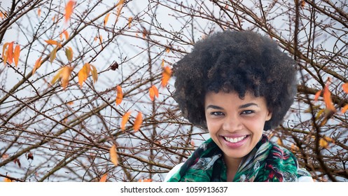 Smiling Woman With Frizzy Hair Against Autumn Branches