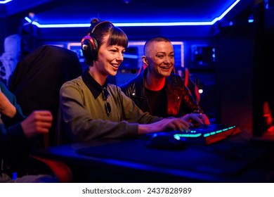 Smiling woman gamer playing PC video game and having fun with her friends. Female video game player participating on a cybersport tournament in a Esports arena or on a Gaming convention. - Powered by Shutterstock