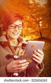 Smiling Woman In Glasses Using Digital Tablet Against Autumn Scene