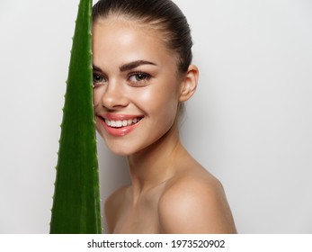 smiling woman with green aloe leaf on light background cropped view closeup portrait