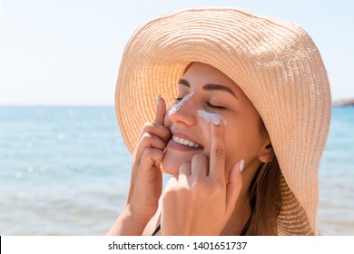 Smiling woman in hat is applying sunscreen on her face. Indian style. - Shutterstock ID 1401651737