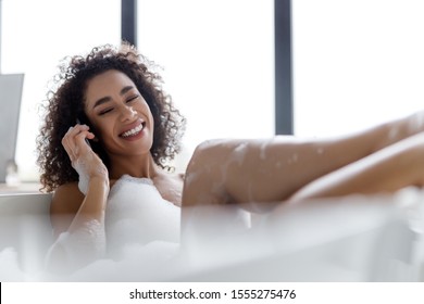 Smiling woman having phone conversation while taking bath stock photo - Powered by Shutterstock