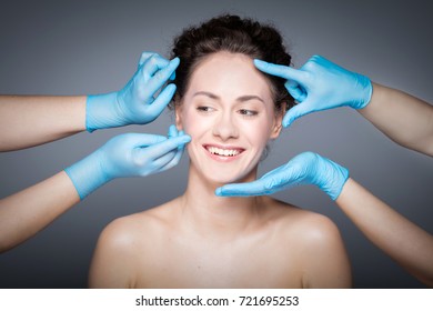 Smiling Woman Having Skin Checkup Before Plastic Surgery. Hands In Gloves Measuring And Touching Woman's Face.