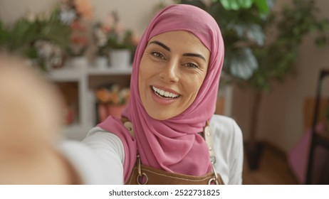 Smiling woman in hijab taking selfie in cozy room filled with plants and home decor. - Powered by Shutterstock