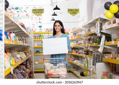 Smiling woman holding a blank sign with supermarket