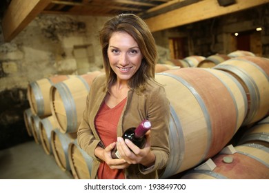 Smiling Woman Holding Bottle Of Wine In Cellar