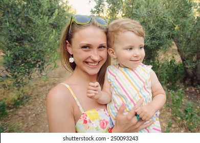 Smiling Woman Holding Child In Arms