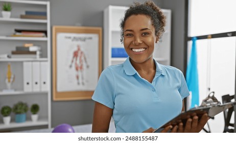 Smiling woman holding clipboard in a physical therapy clinic interior with anatomical posters and exercise equipment. - Powered by Shutterstock