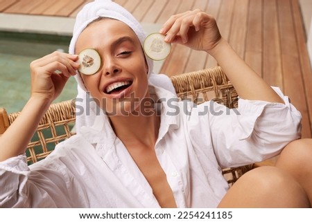 Smiling Woman Holding Cucumber Slices. Young Bathrobe Girl Having Fun at Street. Concept of Skincare