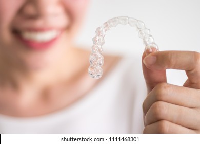 A Smiling Woman Holding Invisalign Or Invisible Braces, Orthodontic Equipment