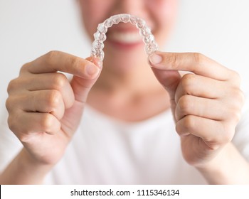 A Smiling Woman Holding Invisalign Or Invisible Braces, Orthodontic Equipment