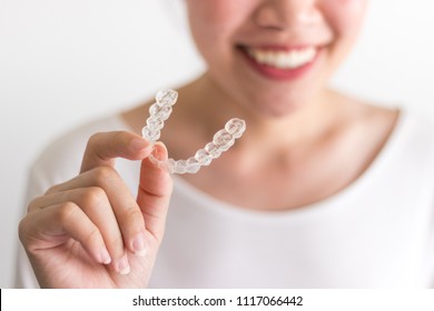 A Smiling Woman Holding Invisalign Or Invisible Braces, Orthodontic Equipment