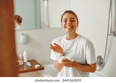 Smiling woman holding jar with skincare cream in hands. Home beauty routine - Powered by Shutterstock