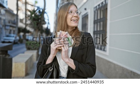 Smiling woman holding norwegian kroner on a sunny city street, exemplifying urban lifestyle and finance.