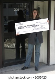 Smiling Woman Holding An Oversize Tax Refund Check. Focus On The Check.