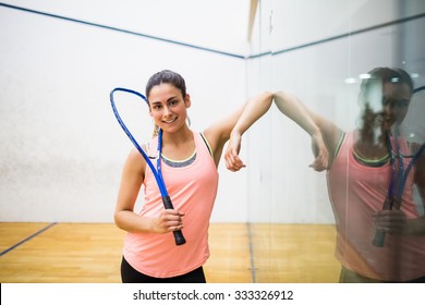 Smiling woman holding a squash racket in the squash court