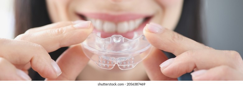 Smiling Woman Holds Clear Plastic Mouthguard To Straighten Teeth