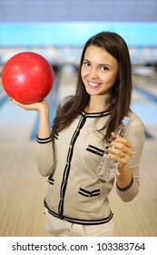 Smiling Woman Holds Red Ball And Bottle With Water In Bowling Club; Shallow Depth Of Field