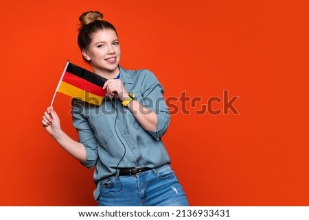 Smiling woman holds small German flag. Female student recommending foreign language studying school. Learning german, deutsch. student exchange and travel concept