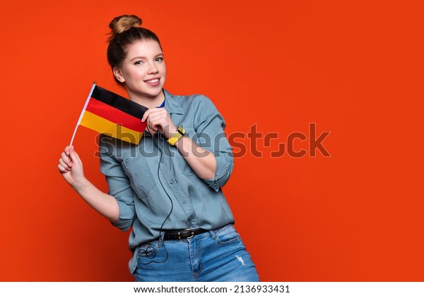 Smiling woman holds small\
German flag. Female student recommending foreign language studying\
school. Learning german, deutsch. student exchange and travel\
concept